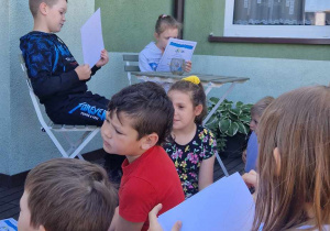 Dzieci uczestniczą w zajęciach czytelniczych na tarasie biblioteki