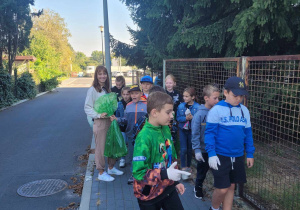 Dzieci sprzątają teren wokół szkoły.