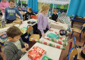 Dzieci uczą się pakować prezenty w pudełkach