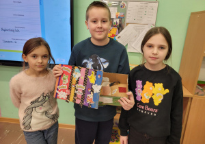 Dzieci prezentują recyklingowe prace plastyczne.