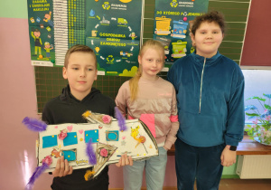 Dzieci prezentują recyklingowe prace plastyczne.