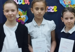 Uczniowie z klasy 3 trzymają dyplomy za udział w szkolnym konkursie recytatorskim