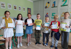 Uczniowie prezentują dyplomy i nagrody za zachowanie i aktywność.