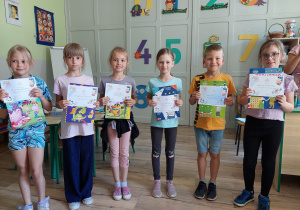 Uczniowie prezentują dyplomy i nagrody za zachowanie i aktywność.